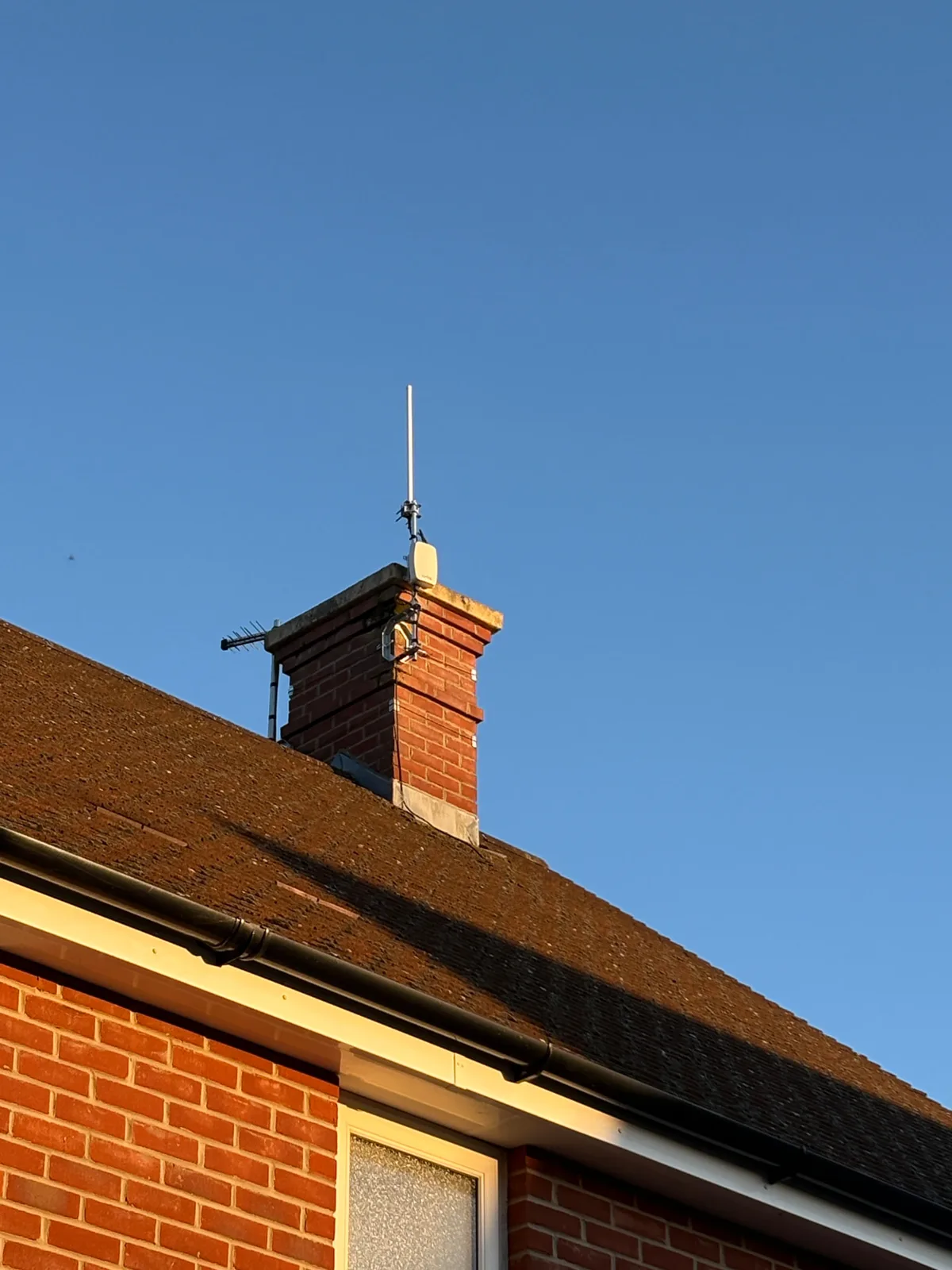 A Netmore LoRaWAN gateway mounted on a UK chimney stack against a bright blue sky